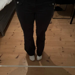 Lågmidjade hm byxor - Trendiga hm byxor utan fickor där bak. Snygga svarta byxor med fickor och knappar framtill. Byxorna har en rak passform och är perfekta för en stilren look. De är tillverkade i ett bekvämt material som ger en skön känsla hela dagen. Storlek 40 men passar 38. Sista bilden ser man en solfläck, syns inte så mycket irl 