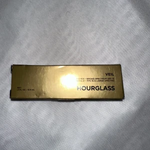 Veil Mineral Primer från Hourglass - Säljer en Hourglass Veil Mineral Primer med SPF 15. Den kommer i en elegant vit och svart flaska. Perfekt för att skapa en jämn bas innan foundation.