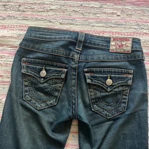  True Religion jeans ❤️ - Säljer ett par mörkblå jeans från True Religion med bootcut passform. Jeansen har dekorativa bakfickor med tydliga sömmar och låg midja.😍😍😍 pris kan diskuteras. Mått: midja rakt över 40,5cm innerben  76 cm❤️❤️