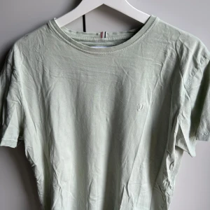 Ljusgrön t-shirt från Les Deux - Snygg ljusgrön t-shirt från Les Deux med diskret broderad logga på bröstet. Klassisk rund halsringning och korta ärmar. Perfekt inför sommaren!