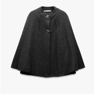 Mörkgrå cape från Zara - Säljer en snygg mörkgrå cape från Zara med två metallspännen framtill. Den går att använda både som en lättare jacka men även som ett inomhus plagg. Den är helt slut på hemsidan!!❤️ Endast använd en gång och i nyskick!!