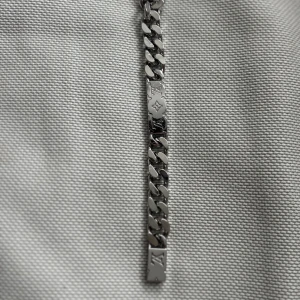 Silverfärgat armband från Louis Vuitton - Säljer ett armband i silverfärg från Louis Vuitton med klassiska LV-loggor och gravyr. Armbandet har breda länkar och en stilren, exklusiv känsla. Perfekt för dig som vill ha en statement-accessoar. Tyvärr så är den för kort för mig och gillar inte stilen längre. När jag köpte det trodde inte jag att den skulle säljas och därför slängde jag tyvärr kartongen med kvittot. Såklart är den äkta.