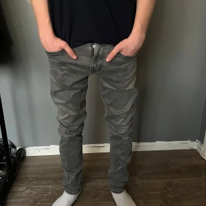 Replay jeans grå  - Säljer ett par grå jeansbyxor med slim passform. Byxorna har klassisk femficksdesign, dragkedja och knapp framtill samt snygga sömdetaljer på bakfickorna. Perfekta för en stilren och enkel look.