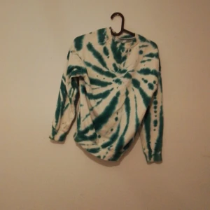 Tie-dye långärmad tröja med NASA-tryck - Säljer en långärmad tie-dye tröja i vitt och grönt med stort NASA-tryck på ryggen. Tröjan har rund hals och är perfekt för dig som gillar rymd och coola mönster. Den är i storlek 134/140 barnkläder.