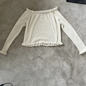 Offshoulder ribbad topp i vitt - FÖRSTA BILDEN ÄR LÅNAD‼️Säljer en söt offshoulder topp i vitt med ribbat material och volangdetaljer vid halsringning, ärmslut. Storlek L men passar mig som är XS-XXS😊