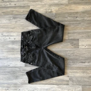 Svarta Replay Hyperflex jeans - Säljer ett par svarta Replay Hyperflex jeans med klassisk femficksdesign och snygga detaljer på fickorna. Jeansen är tillverkade i stretchigt material för extra komfort. Perfekta för dig som gillar stilrena och bekväma jeans.