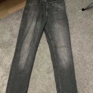 Grå jeans Regular/Clark - Säljer ett par grå jeans i modellen Regular/Clark med klassisk femficksdesign och raka ben. Jeansen har en snygg tvättad look och passar perfekt till vardagsstilen. Storlek  W30 L32.