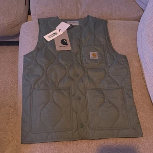 Grön quiltad väst från Carhartt - Aldrig använd, lapp finns kvar. Storlek XS men passar även S. Kan gå ner i pris vid snabb affär. Köpt för 1495kr