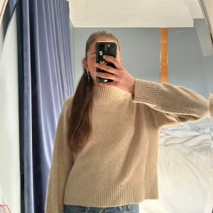 Beige stickad tröja med rund hals - Säljer en beige stickad tröja med lite polo och långa ärmar. Tröjan har en rak, något loose passform och ribbade muddar vid ärmslut och nederkant. Storlek Xs men är lite större 