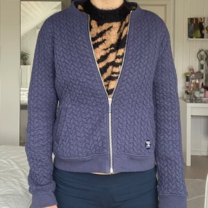 Blå quiltad jacka från Barbour - Säljer en blå quiltad jacka från Barbour med dragkedja framtill. Jackan har långärmad passform och ett diskret Barbour-märke på vänster sida. Mjuk och bekväm med strukturmönster över hela plagget.