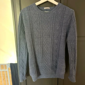 Gant kabelstickad tröja  - Säljer en blå stickad tröja med klassiskt kabelstickat mönster. Tunn och perfekt till vår eller sommarkvällarna 
