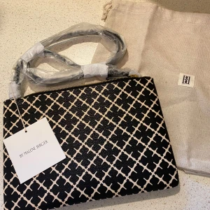 Svart och beige axelväska från By Malene Birger - Säljer en snygg axelväska från By Malene Birger i svart och beige med grafiskt mönster. Väskan har guldfärgad dragkedja och kommer med dustbag. Perfekt för att lyfta din outfit! Nypris 900kr