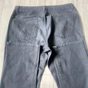 Grå jeansbyxor  - Snygga grå jeansbyxor från Mingel Jeans med raka ben och dekorativa strasstenar på bakfickorna. Klassisk femficksmodell med knapp och dragkedja framtill. Perfekta för dig som vill ha en stilren look med lite extra detaljer.