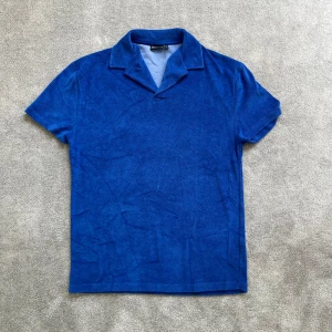 Blå frotté piké - Säljer en blå piké/t-shirt i mjuk frotté då den aldrig kommit till användning -  nästintill ny! På lappen står det XXS, men passar snarare S-XS då den är större i storleken. Jag svarar snabbt, så det är bara att höra av dig vid minsta fundering!