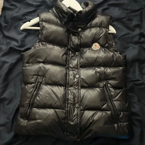Moncler vest - Skön moncler vest svart färg, den e äkta köpt från new york enligt förra ägaren, kan skicka bild på hans annons vid önskemål, hör av er vid intresse, dragkedjan på fickan va paj förut men jag har fixat den så den e som den ska