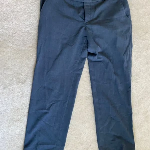 Mörkblå kostymbyxor från Bexleys - Säljer ett par mörkblå kostymbyxor från Bexleys med klassisk passform och två bakfickor med knappar. Byxorna har komfortmidja och är tillverkade i ett lätt tyg som passar perfekt till mer uppklädda tillfällen.