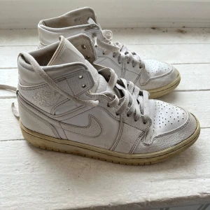 Vita Nike Air Jordans sneakers - Säljer ett par klassiska vita Nike Air Jordans sneakers. Skorna har en ikonisk Nike-logga på sidan.