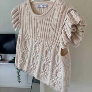 Ljusrosa stickad topp med volangärmar från Zara - Superfin ljusrosa stickad topp från Zara med korta volangärmar och snyggt mönster. Perfekt att styla till jeans eller kjol för en trendig look.