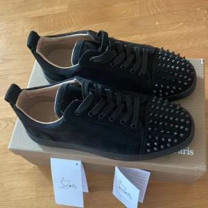 Svarta sneakers med nitar, skriv ifall intresserad! - Säljer ett par svarta sneakers från Christian Louboutin med coola svarta nitar framtill. Skorna har snörning och är gjorda i mocka med en platt sula. Perfekta för dig som vill sticka ut med din stil. Allt OG följer med förutom skohornet!                Pris kan diskuteras vid snabbt köp.