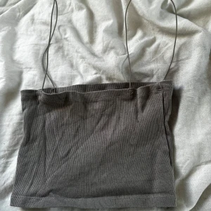 Grå ribbad linnetopp från Pull&Bear - Säljer en grå ribbad linnetopp från Pull&Bear med tunna axelband. Perfekt att styla till jeans eller kjol för en enkel och trendig look.