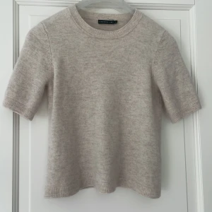 Beige stickad tröja från Stockh LM - Mysig beige stickad tröja från Stockh LM med korta ärmar och rund halsringning. Tröjan har en enkel och stilren design, perfekt för lager-på-lager och passar till många olika outfits. Väldigt liten i storlek så skulle säga att den är xxs/ xs.