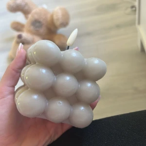 Grå bubbel-ljus - Säljer ett grått bubbel-ljus i unik och modern design. Ljuset har en kubformad bas med rundade bubblor över hela ytan och en vit veke på toppen. Perfekt som dekoration i hemmet.