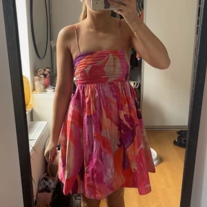 Färgglad kortklänning med tunna axelband - Säljer en färgglad kortklänning med tunna axelband och mönster i rosa, rött, orange och lila. Storlek xs! 