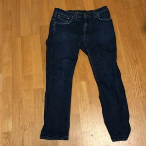 Mörkblå jeans från Nudie - Säljer ett par mörkblå jeans från Nudie Jeans med klassisk femficksdesign. Byxorna har raka ben och normal passform, perfekt för dig som gillar stilrena jeans med häftiga små detaljer!🤩kom dm om ni har några funderingar eller frågor. Det låga priset på 50kr är inte riktiga priset så ni får komma med rimliga prisförslag 🙌