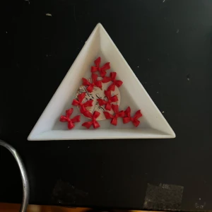 Nail art - Säljer Nail art som är formade som röda rosetter. Perfekta för att ge en fin detalj till dina naglar.  Passar dig som gillar färgglatt.