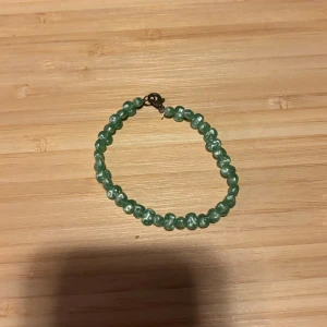 Grönt pärlarmband - Snyggt armband med gröna pärlor och metallspänne. Perfekt för att ge lite färg till din outfit. Passar både till vardags och när du vill sticka ut lite extra.