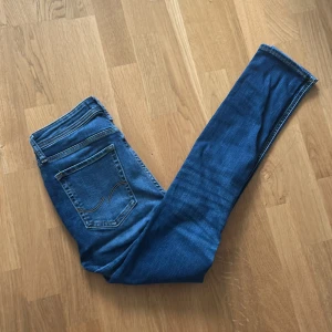 Blå jeans från Jack&Jones - Säljer ett par klassiska blå Slim jeans från Jack&Jones. Byxorna har fem fickor, smal passform och storlek 28 i midja. Perfekta till vardags och lätta att matcha med olika stilar.