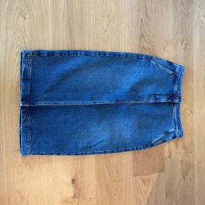 Jeanskjol från Dagmar - Säljer en klassisk blå jeanskjol från Dagmar i rak modell. Kjolen är tillverkad i ekologisk bomull. Perfekt till vardags med en enkel t-shirt eller stickad tröja.