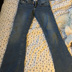 Blå jeansbyxor från Gina Tricot - Säljer ett par klassiska blå jeansbyxor från Gina Tricot med två knappar i midjan och raka ben. 