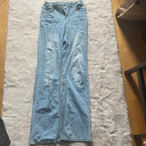Ljusblåa bootcut jeans - Säljer ett par ljusblå jeans med bootcut och klassisk femficksdesign. Jeansen har låg midja, vida ben som ger en avslappnad och trendig look. Perfekta till sneakers eller boots för en chill vibe.