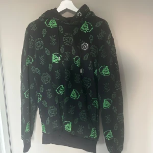 Svart hoodie Philipp Plein -  svart hoodie från Philipp Plein med gröna döskallar, blixtar och loggor broderade över hela tröjan. Tröjan har huva. Limited edition nypris ca 11000 säljer då den inte passar mig hör av er för fler och och bättre bilder osv.