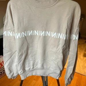 Beige sweatshirt från N-brand - Säljer en beige sweatshirt från N-brand med vitt grafiskt mönster runtom bröstet. Tröjan är i 100% bomull och har långa ärmar samt ribbade muddar vid ärmslut och nederkant. Perfekt för en avslappnad stil.🩷
