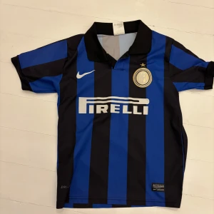 Inter Milan matchtröja med Pirelli sponsor - Klassisk Inter Milan fotbollströja med blå och svarta ränder, Pirelli-logga på bröstet och Nike-märke. Nummer 9 och namn Forlan på ryggen. Kortärmad modell med krage och klubbmärke på bröstet. Säljer båda för 200 totalt
