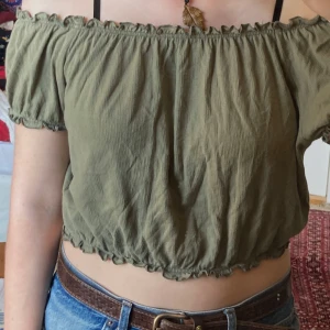 Olivgrön offshoulder topp, S - Söt sommar topp. Den är olivgrön croppad offshoulder från KappAhl med korta puffärmar och resår vid halsringning och nederkant. Tunt, luftigt bomullstyg. Som ny, inga defekter.