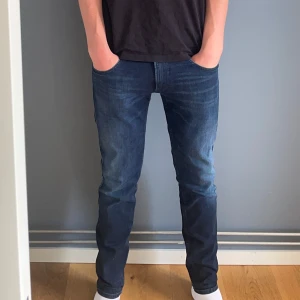 Mörkblå Replay jeans slim fit - Snygga mörkblå jeans från Replay med klassisk femficksdesign. Modellen har rak passform och normal midja, perfekt för en clean och stilren look. Jeansen är gjorda i mjukt denimtyg med lite stretch för extra komfort.