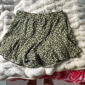Grön skort med vita och orangea blommor på. - Skön, bra kvalitet 