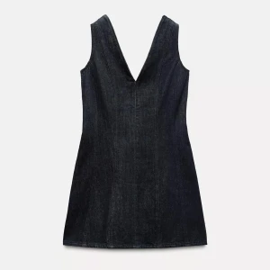 Mörkblå jeansklänning - Snygg mörkblå jeansklänning med djup v-ringning både fram och bak. Klänningen är ärmlös och har en kort, figurnära passform som ger en cool och modern look. Perfekt att styla med boots eller sneakers för en trendig outfit. Uppsydd där nere då jag är 155cm så passar någon som är runt där. Stolek xs 