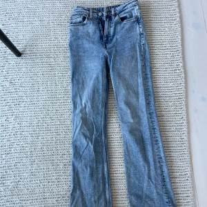 Blå bootcut jeans  - Säljer ett par klassiska blå bootcut jeans från Monki i storlek w26. Jeansen har normal passform, fem fickor och stängs med dragkedja och knapp. Perfekta till vardags för en avslappnad men snygg look.