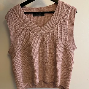 Rosa stickad väst från Primark - En söt, stickad väst i ljusrosa från Primark. Västen har v-ringning och breda ribbade kanter vid hals och ärmhål. Perfekt att styla över en skjorta eller t-shirt för en trendig lager-på-lager-look.