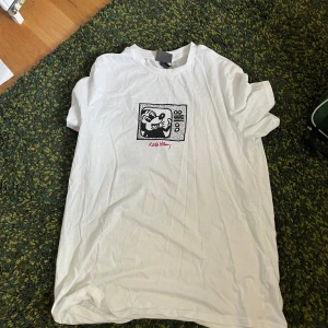 Vit t-shirt med Mickey Mouse-tryck från H&M - Vit t-shirt från H&M med ett svartvitt tryck av Mickey Mouse och texten 'Kids Mickey' på bröstet. Klassisk rund hals och korta ärmar. Perfekt för dig som gillar Disney och streetstyle.