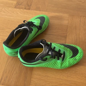 Gröna Nike Hypervenom fotbollsskor Storlek 33 - Säljer ett par gröna Nike Hypervenom fotbollsskor med svart sula och snörning. Skorna har svart Nike-logga och cool dödskalle-detalj på hälen. Ovandelen är i syntetmaterial med textur för bättre bollkontroll. Perfekta för dig som vill sticka ut på planen. Bästa skorna för ditt barn för ett bra pris. Ganska Rare fotbollskor.