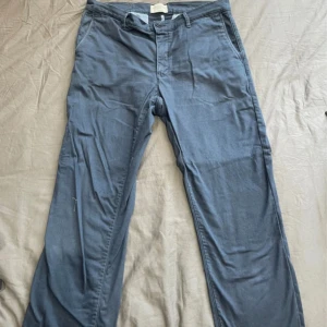 Blåa och gröna chinos från These Glory Days  - Snygga blå och gröna chinos från These Glory Days. Båda ingår i samma pris. Klassisk rak passform med dragkedja och knapp i midjan. Perfekta för en stilren och avslappnad look. Tillverkade i mjuk bomull för extra komfort.