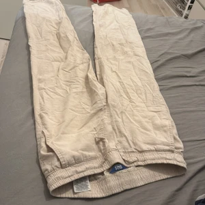 Beiga mjukisbyxor med resårmidja - Beiga linnebyxor från  Jack and Jones med resår i midjan och raka ben. Byxorna har sidfickor och en bakficka. Perfekta för en avslappnad stil och sköna att ha på sig i sommar! 