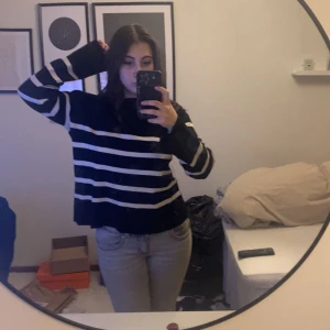 Svart och vit randig stickad tröja - Säljer en svart stickad tröja med vita horisontella ränder. Tröjan har lång ärm och en avslappnad passform. Perfekt för dig som gillar en enkel men stilren look.