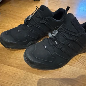 Adidas vandringsskor/sneakers med snabbsnörning - Perfekta skor för friluftsliv/vandring i fjällen. Nyskick och aldrig använda. De är i storlek 44 men känns lite för små för mig. Så jag skulle säga de passar storlek 42-43 berorende på hur bredda fötterna är.