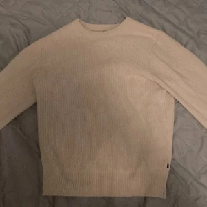 Beige stickad tröja J.Lindberg - Säljer en stilren beige stickad tröja i mycket bra skick. Perfekt för kyliga höst- och vinterdagar. Tröjan har en klassisk design med rund hals och långa ärmar. Den är mjuk och bekväm, idealisk för både vardag och lite finare tillfällen. Pris kan diskuteras 